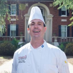 Chef Bear Evans standing in front of Spigner House smiling in chef coat