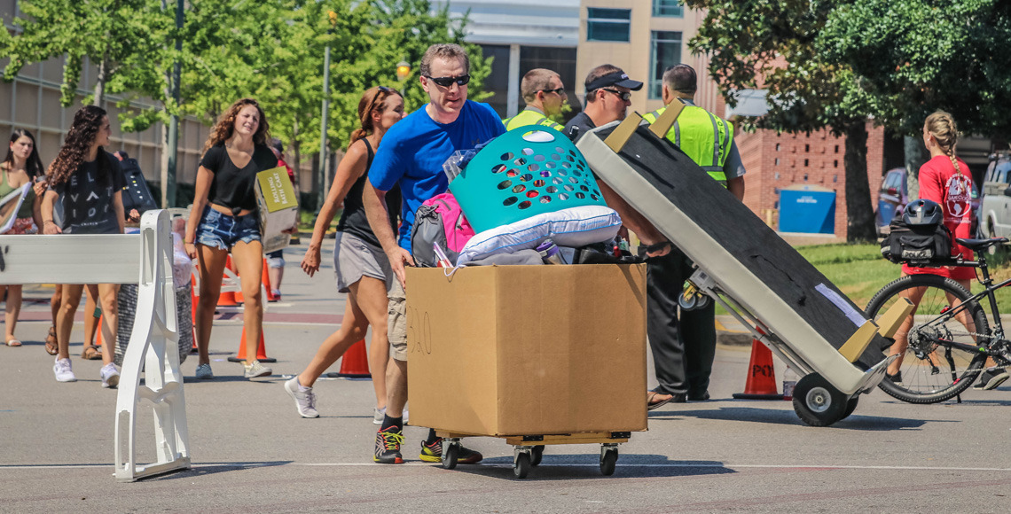 Students with their parents pushing the move-in carts across the road into Patterson Hall on move-in day 