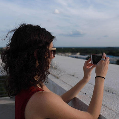image of student taking a selfie on the top of a parking garage while filming a student takeover